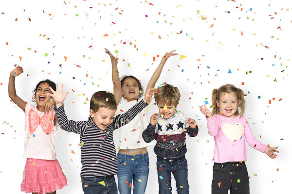 Five young children dance and play in falling confetti.
