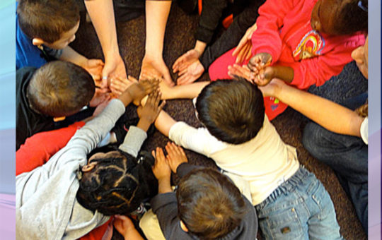 A Diverse group of kids puts their hands together in a circle.