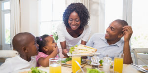 African american family of woman, man and young girl eating at dinner table