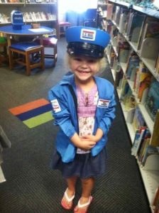 Smiling girl wears a U.S. mail carrier play uniform