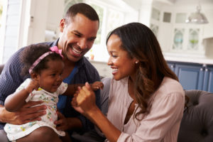 african american couple sitting on couch with baby girl