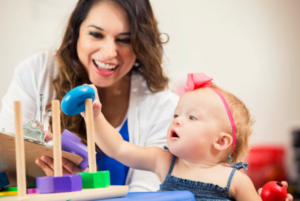 smiling woman and toddler playing with stacking toy