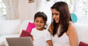 A mother and her young daughter watch a video together on a laptop