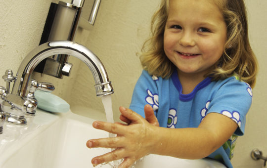 little girls smiles while she is washing her hands