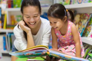 mother and daughter smile while looking at a book