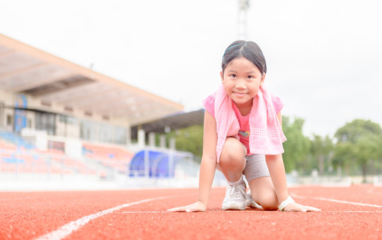 young girl in running position at start line of race