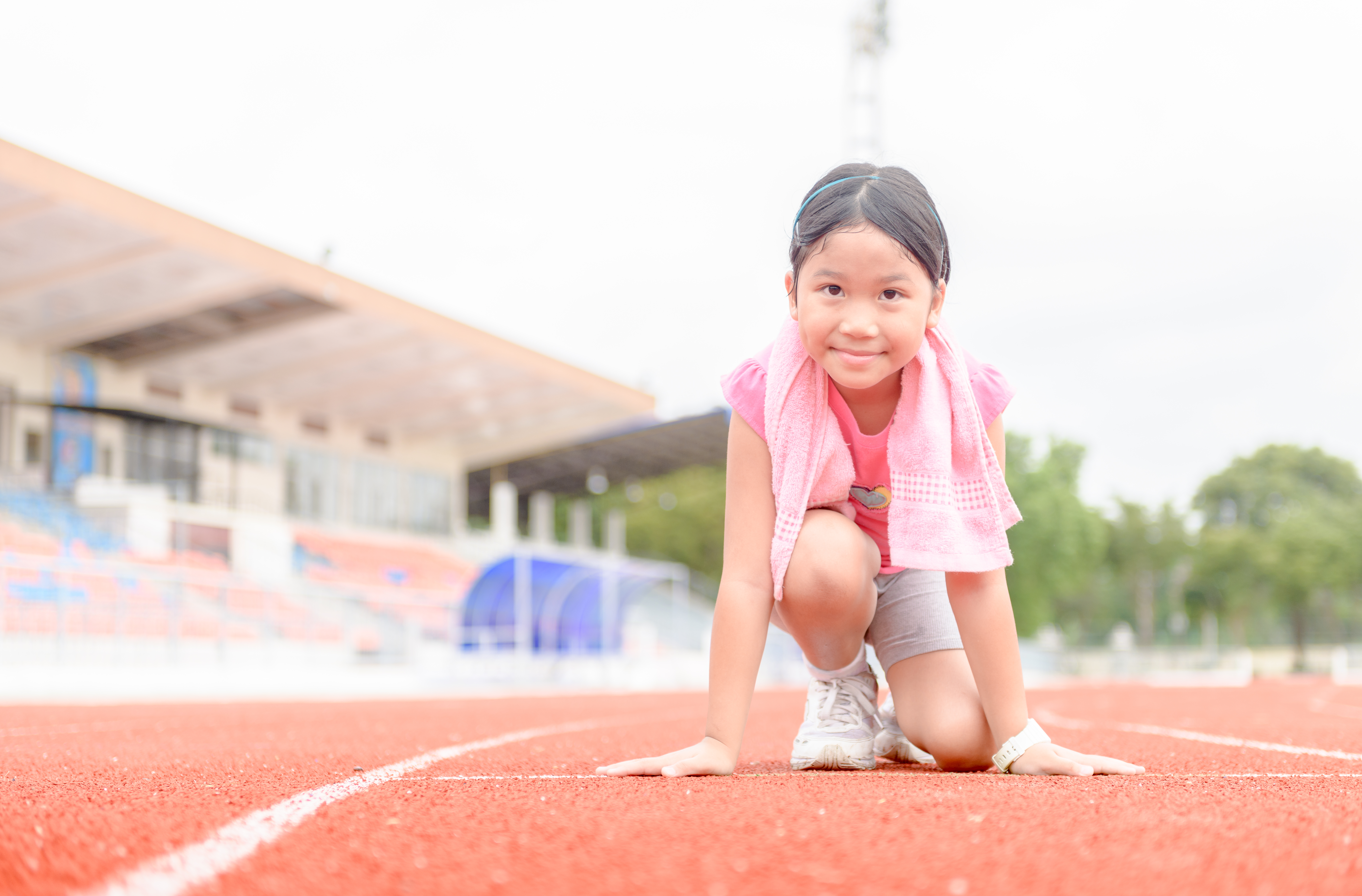 young girl in running position at start line of race