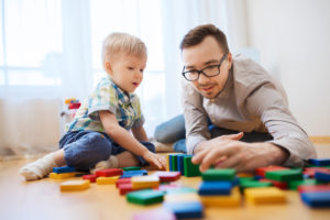 man sits on the floor with this son playing with blocks