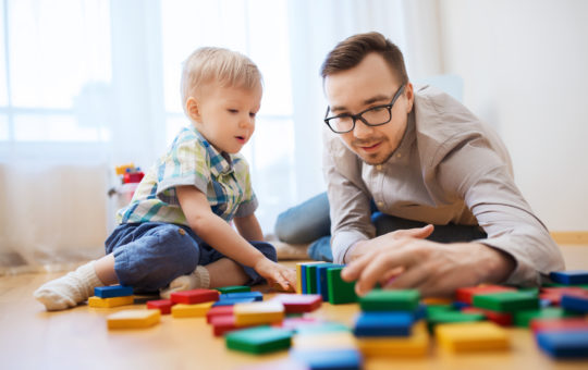 man sits on the floor with this son playing with blocks