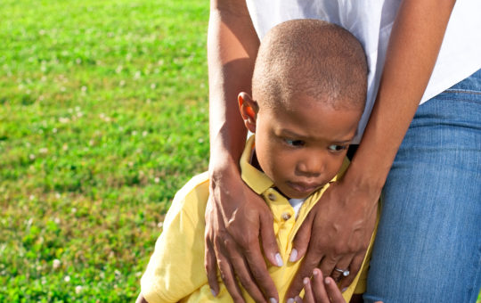 a young african american boy is comforted by his mom