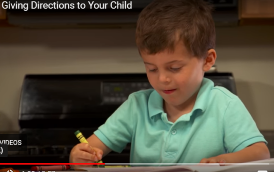 video screenshot of boy sitting at kitchen counter coloring