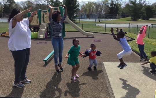 Adults and children play and jump together on a playground