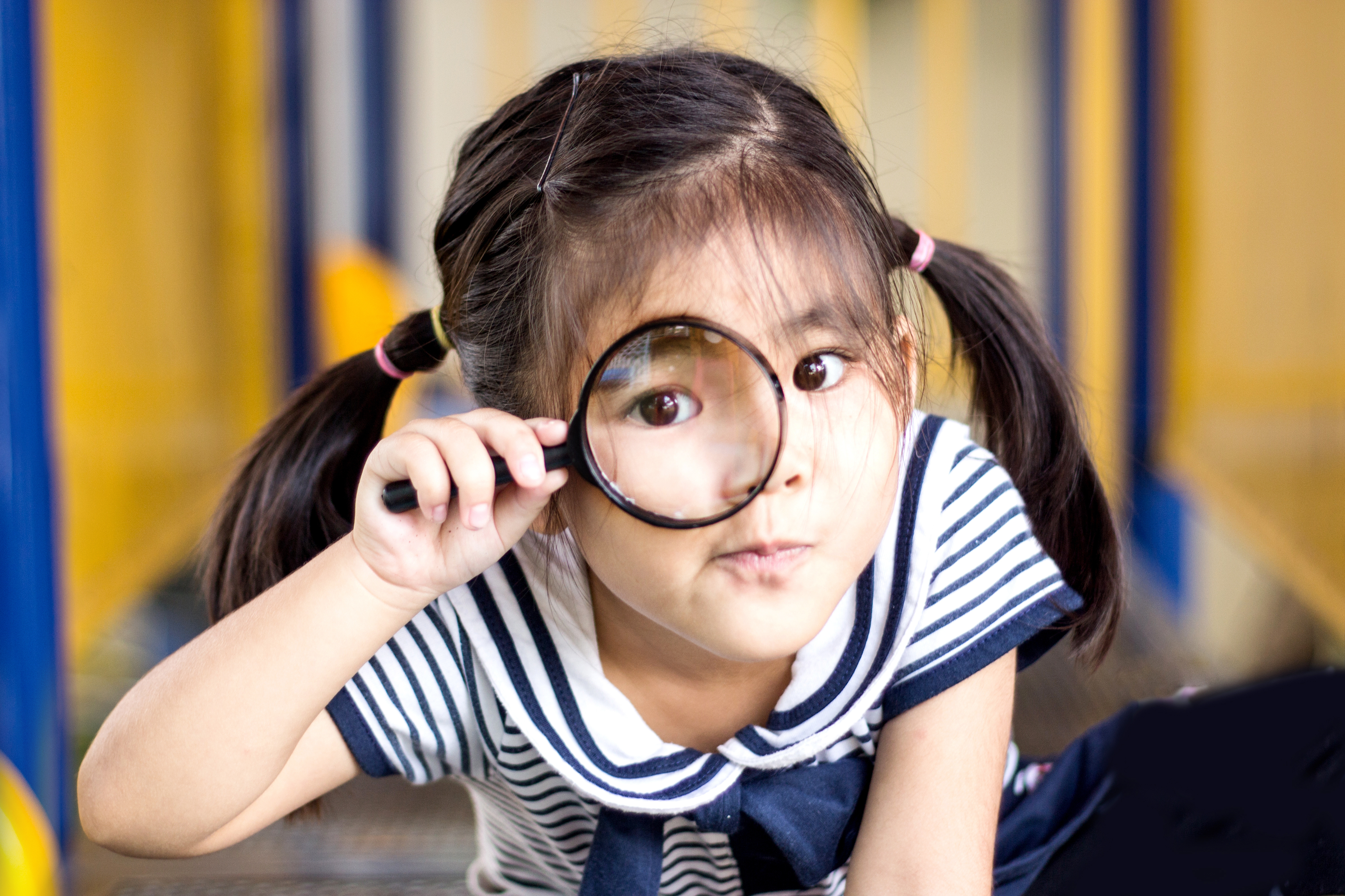 Young girl holds magnifying glass up to her eye