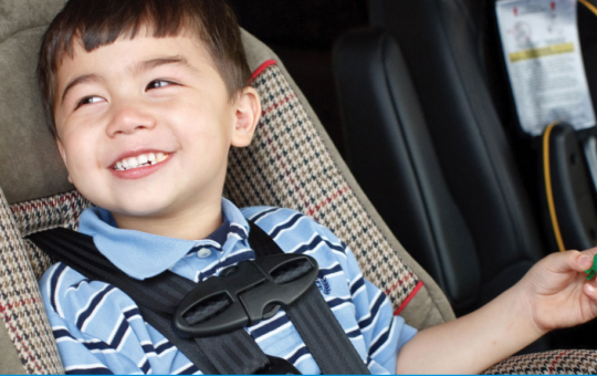 Preschool boy smiles in his car seat