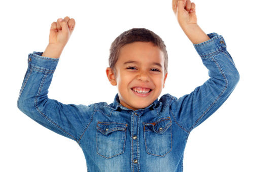 boy with smile raises his hands in accomplishment