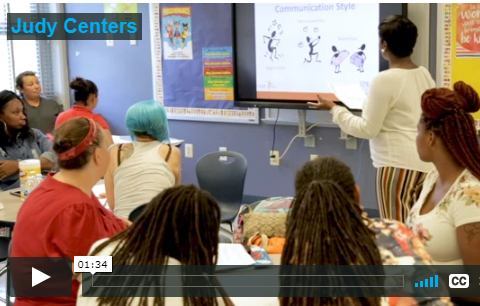 video screenshot showing a facilitator in front of a room full of parents and families