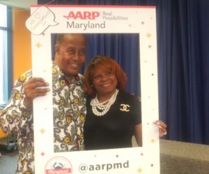 Grandparents and granddaughter holding AARP Maryland photo border.