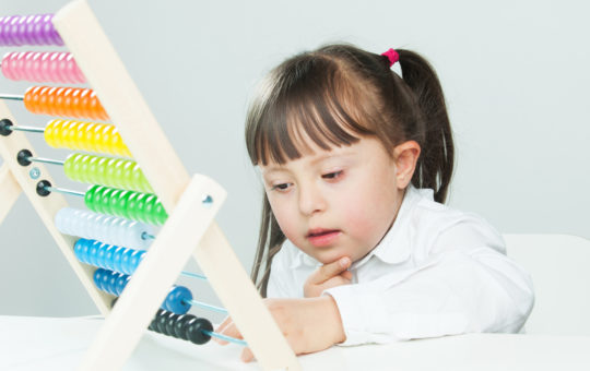 a girl lies on her belly manipulating the beads on an abacus